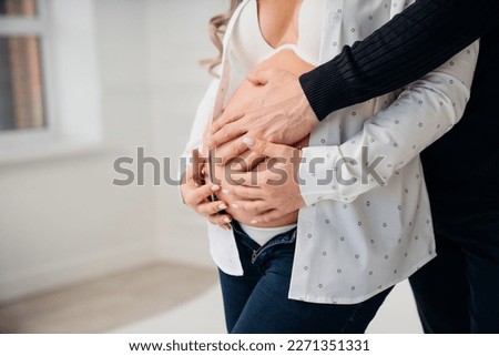 a man's hand on the stomach of a pregnant woman. the concept of women's health and family happiness. surrogate motherhood and artificial insemination. 