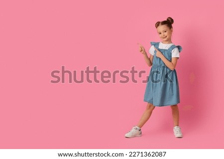 Check This. Cute Little Girl Pointing Aside At Copy Space With Two Fingers While Standing Over Pink Studio Background, Smiling Female Child Demonstrating Free Place For Design Or Offer