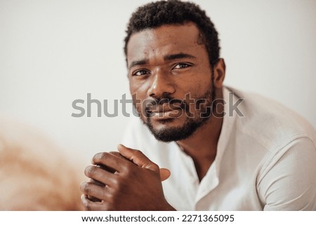 Candid millennial authentic diverse portrait of african american man relax time at apartment in neutrals tones interior.Domestic life multi ethnic male having thoughtful facial expression in day light Royalty-Free Stock Photo #2271365095