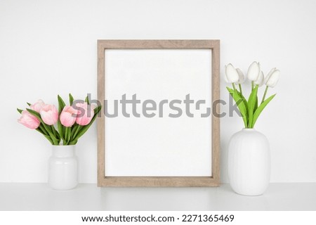 Mock up wood frame with spring tulip flowers. White shelf against a white wall. Copy space.