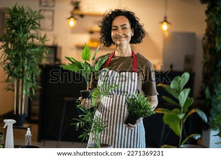 One woman mature caucasian female stand at home with flower plants pot happy smile waist up front view gardening and botany horticulture care concept copy space
