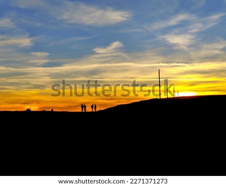 High contrast sunset with outlined people silhouettes on the horizon and negative black space in the bottom half