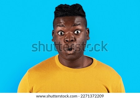 Omg. Closeup Portrait Of Shocked Young African American Man, Young Black Male Looking At Camera With Surprise And Opening Mouth While Standing Isolated Over Blue Studio Background, Copy Space