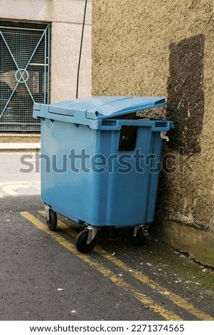 Small wheelie bin in an alley or street ready for collection. Rubbish disposal and management in a city. Royalty-Free Stock Photo #2271374565