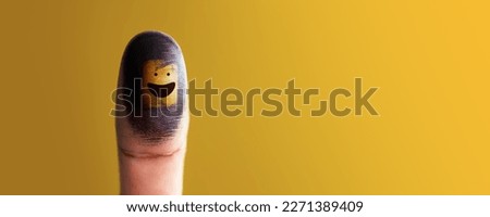 Happiness Day Concept. Happy and Positive Mind, Well Mental Health. Enjoying Life Everyday. Smiling Face on Thumb against Yellow Wall