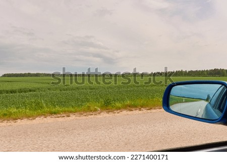 Driving a car through the green country fields and forest on a sunny day. Clear blue sky. Idyllic rural scene, concept landscape. Nature, remote places, logistics, summer vacations, road trip