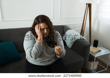 Depressed hispanic woman crying feeling sad while looking at her engagement ring after a heartbreaking breakup from her ex-fiance