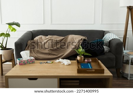 Depressed sad young woman lying on the sofa hiding under the covers while crying and missing her ex-boyfriend after a break-up