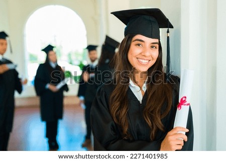 Beautiful hispanic woman smiling making eye contact after getting her university diploma at a graduation ceremony on campus Royalty-Free Stock Photo #2271401985