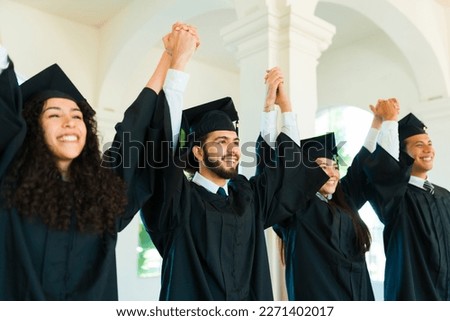 Attractive friends graduates holding hands and celebrating during their university graduation ceremony Royalty-Free Stock Photo #2271402017