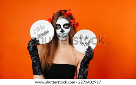 Photo of a girl in Halloween makeup and flower holding some Halloween cartoons.