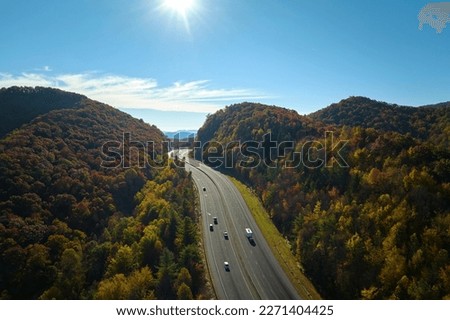View from above of I-40 freeway route in North Carolina leading to Asheville thru Appalachian mountains with yellow fall woods and fast moving trucks and cars. Interstate transportation concept Royalty-Free Stock Photo #2271404425