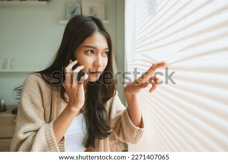 Young asian woman using mobile smartphone and looking at outside window Royalty-Free Stock Photo #2271407065