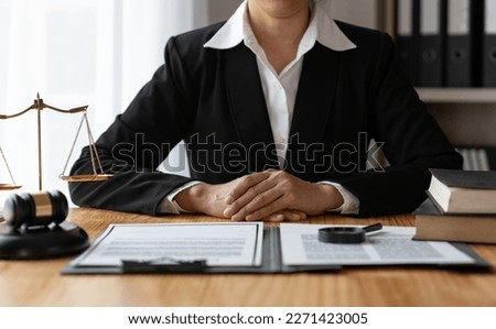 Asian female lawyer or legal counsel sitting at table holding hands listen and use their thoughts with a signed contract agreement and  magnifying glass to verify the accuracy of business data law.