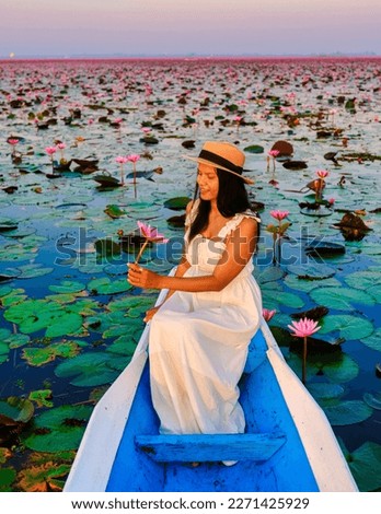 Asian women in a boat at the Beautiful Red Lotus Sea Kumphawapi is full of pink flowers in Udon Thani in northern Thailand. Flora of Southeast Asia.