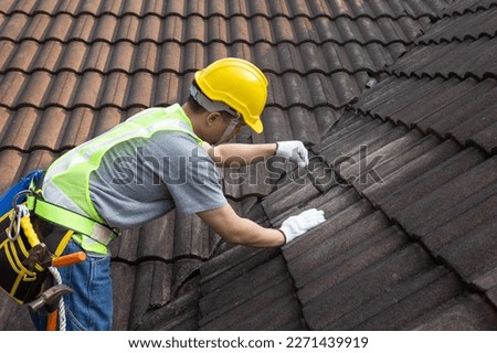 Worker man using waterproof roof coating repair to fix crack of the old tile roof. Royalty-Free Stock Photo #2271439919