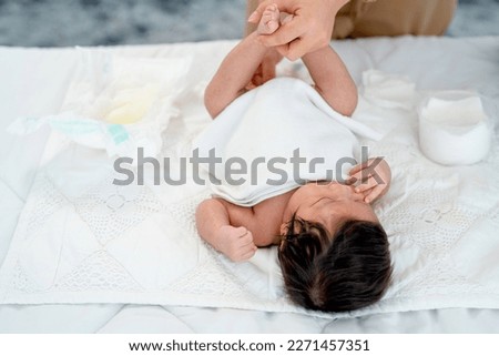 Close up view mother change diaper or napkin for newborn baby lie on white bed after she excrete pee or stool.