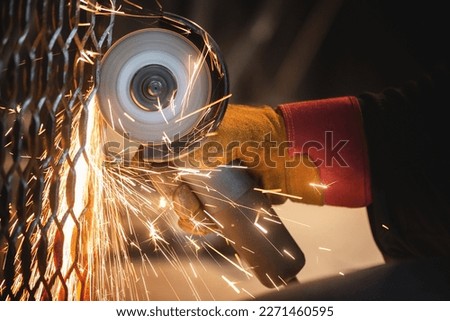 Man is cutting a metal by angle grinder saw.