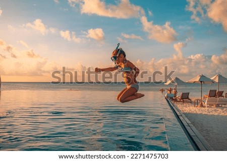 Happy child toddler jumping into infinity swimming pool at sunset as travel lifestyle portrait. Cute girl with blond hair snorkel googles jumps into water splashes water drops. Family summer vacation
