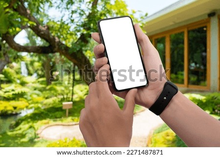 Cropped shot view of man hands holding smart phone with blank copy space screen with blurred background. For Graphic display montage.