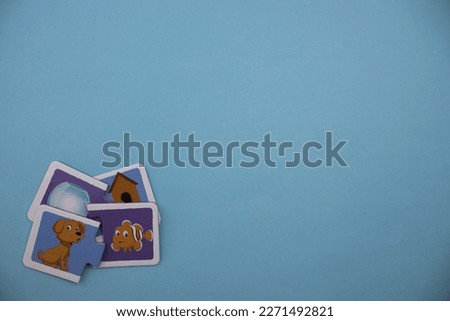 Educational puzzle pieces with pictures of glass bell jar, fish, dog and kennel mixed in the lower left of the blue background.