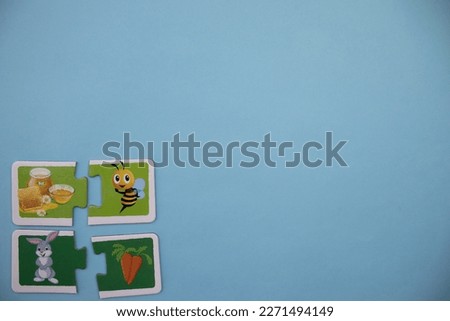 Educational puzzle pieces with pictures of rabbit, carrot, honey bee and honey placed on the lower left of the blue background.