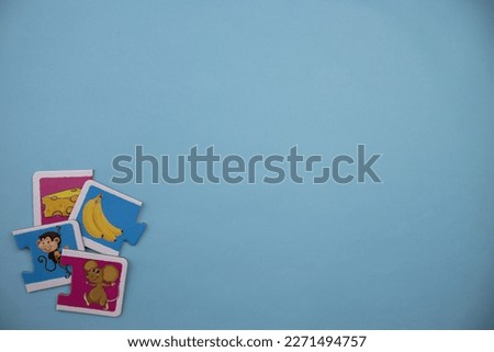 Educational puzzle pieces with pictures of cheese, mouse, banana and monkey mixed up on the lower left of the blue background.