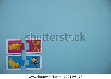 Educational puzzle pieces with pictures of cheese, mice, bananas and monkeys placed on the lower left of the blue background.
