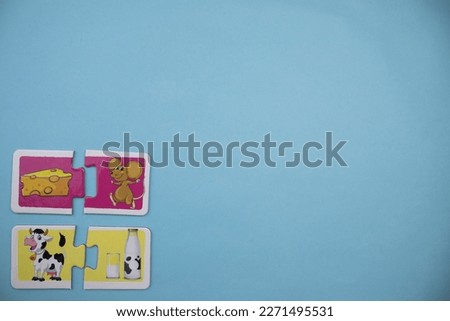 Educational puzzle pieces with pictures of cheese, mouse, milk and cow placed on the lower left of the blue background.