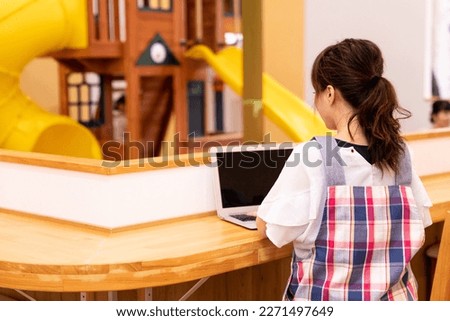Nursery teacher using laptop at nursery school・mom Royalty-Free Stock Photo #2271497649