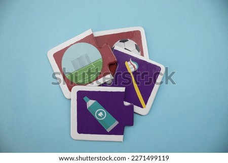 Educational puzzle pieces with pictures of soccer ball, soccer goal, toothpaste, toothbrush mixed arranged on blue background.