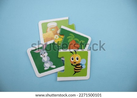Educational puzzle pieces with pictures of carrots, honey, rabbits and honeybees mixed together on a blue background.