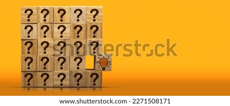 Concept of creative idea and innovation. Group of wooden blocks with brown question marks and a wooden cube with a light bulb, on a yellow and orange background with copy space and reflections