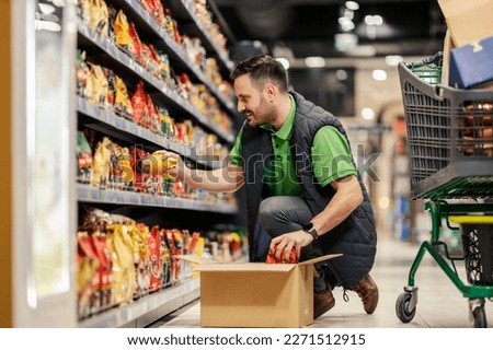 A stock clerk is arranging products on shelves at the supermarket.