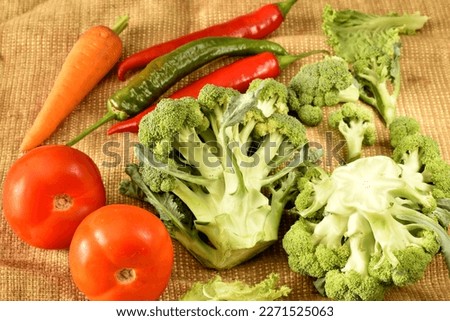 The picture shows a still life composed of ripe carrots, cauliflower, red tomatoes and a few hot chili peppers.