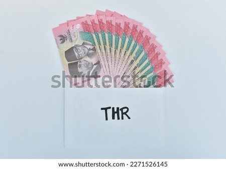 Indonesian Money, rupiah or IDR in envelope with THR Text. The THR envelope contains IDR 100,000 in cash. THR is a holiday allowance on Eid al-Fitr or Eid al-Fitr. best quality white background. Royalty-Free Stock Photo #2271526145