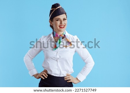 happy stylish flight attendant woman against blue background in uniform. Royalty-Free Stock Photo #2271527749
