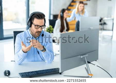 Dedicated male customer service representative communicating with customer trying to provide appropriate solutions for client issues at call center. Royalty-Free Stock Photo #2271552655