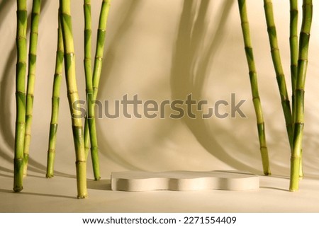 Green bamboo stems and plaster podiums on beige background Royalty-Free Stock Photo #2271554409