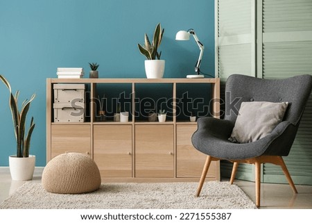 Interior of cozy living room with folding screen, armchair and drawers Royalty-Free Stock Photo #2271555387