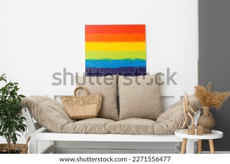 Painting of LGBT flag and couch near light wall in living room