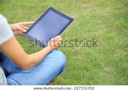 young asian woman college student use tablet pc on grass 
