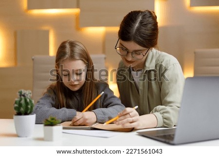 Private lessons at home with a teacher, mom and daughter do their homework. Royalty-Free Stock Photo #2271561043