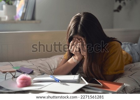 Caucasian teenage girl sitting on bed with head in hands and trying to learn Royalty-Free Stock Photo #2271561281