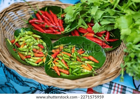 Portrait of red and green bird chilli in blurry red goat pepper, many Thai pepper placed in a wooden basket.