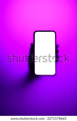 Phone with glowing screen in hand in neon fog as background