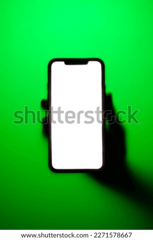 Phone with glowing screen in hand in neon green fog