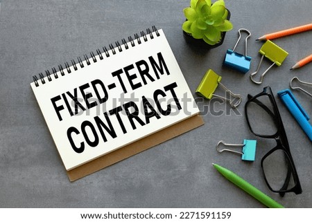 Fixed-Term Contract scattered office supplies on a gray background. text on notebook