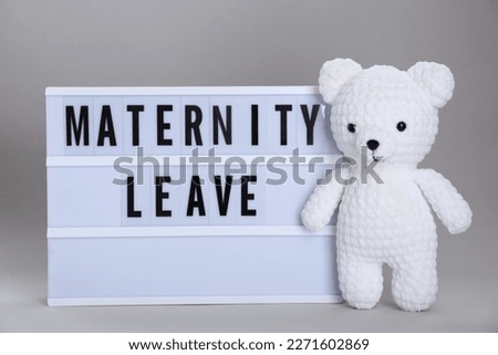 Lightbox with words Maternity Leave and toy bear on light grey background