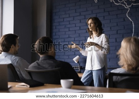 Engaged confident business project female leader talking to team, telling strategy, plan, presenting tasks. Serious pretty presenter girl speaking to coworkers, brainstorming on meeting Royalty-Free Stock Photo #2271604613
